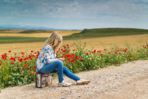 Fille-sur-une-valise-avec-chemin